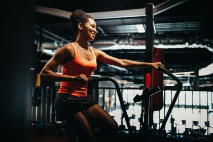 Fitness female using air bike for cardio workout at crossfit gym